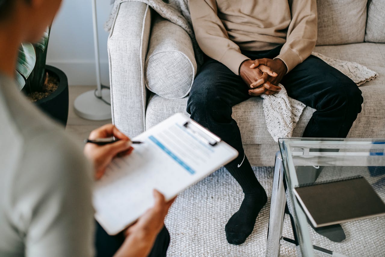 our-services-01 Therapist takes notes as client sits on a sofa during a psychotherapy session.